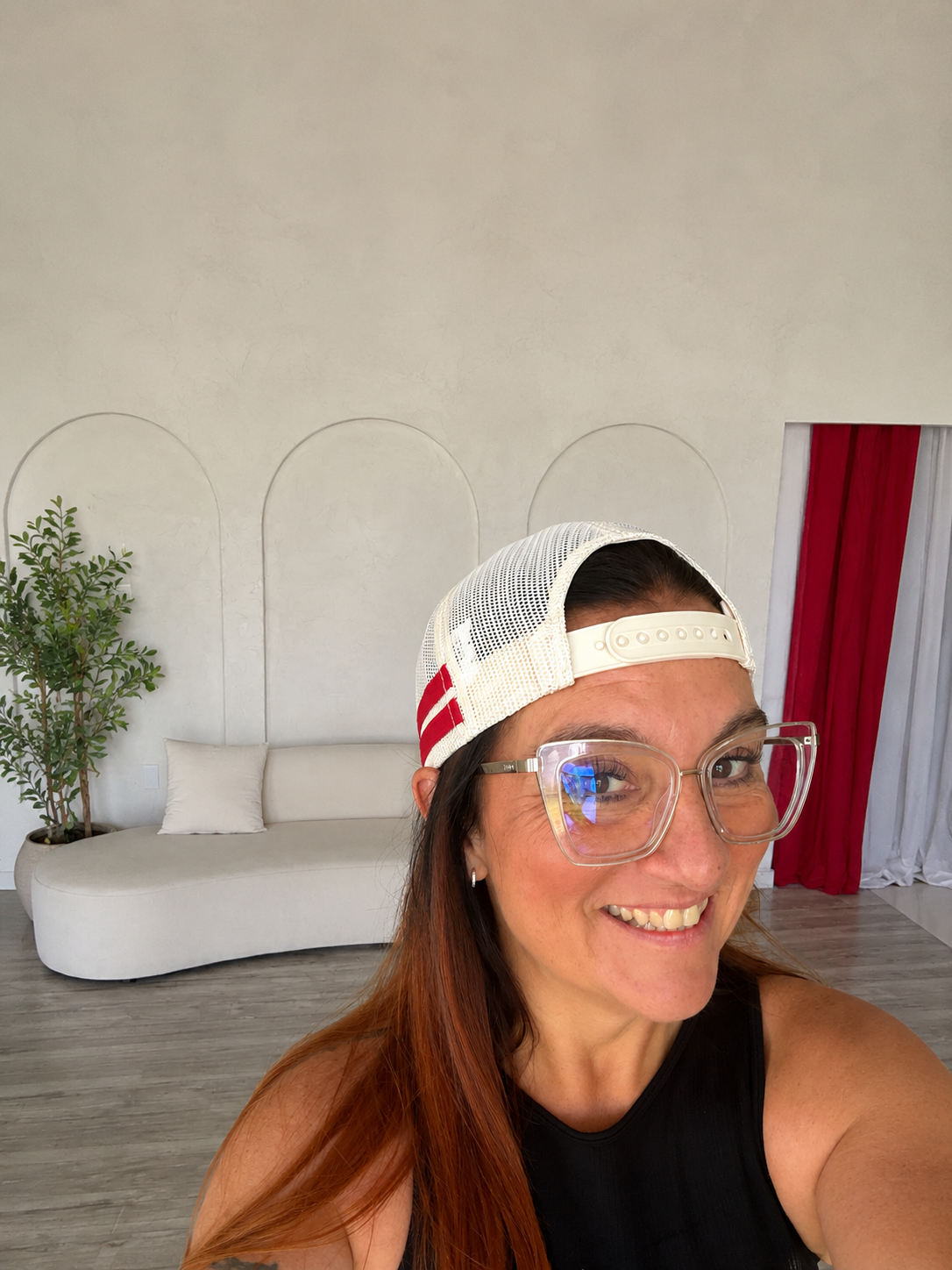 Brand photoshoot behind-the-scenes: woman in glasses and trucker hat smiling